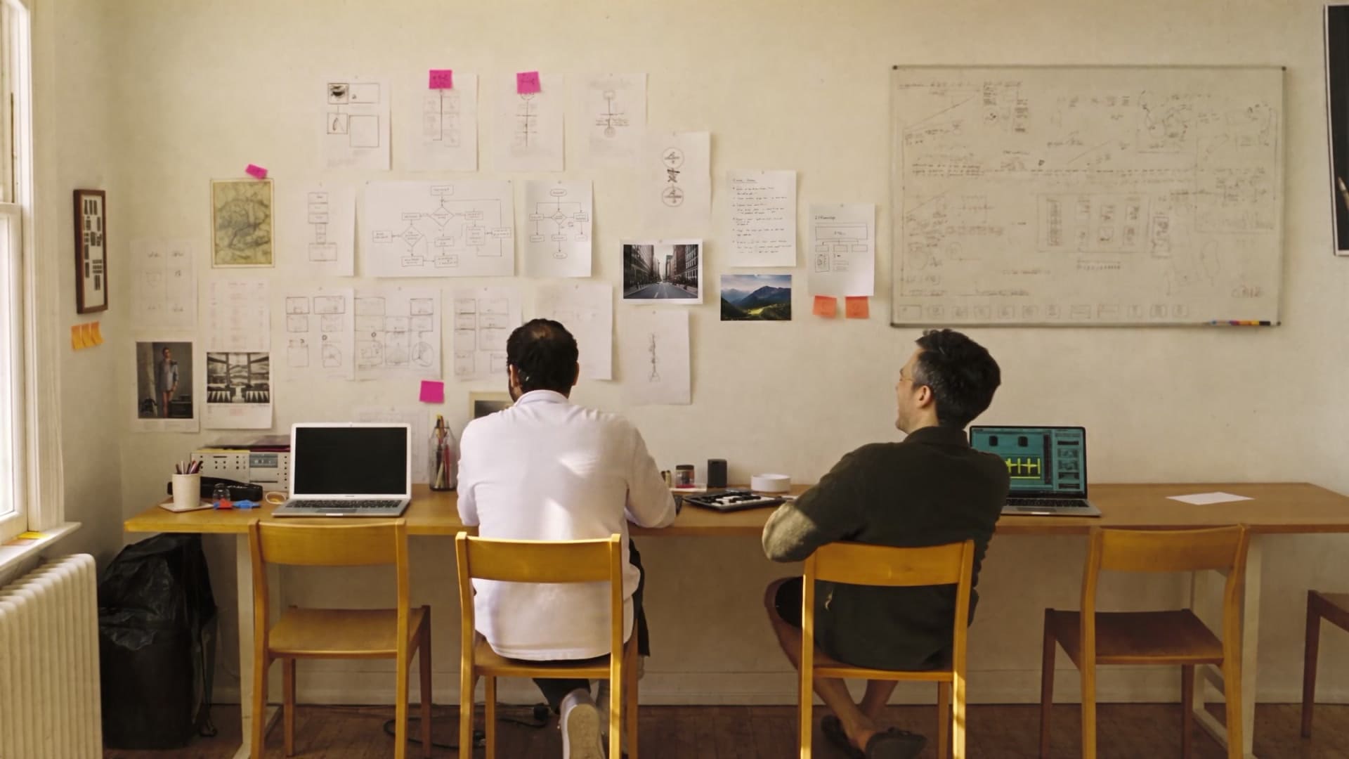 Two people working side by side at a shared desk